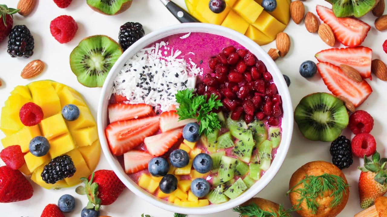 a smoothie bowl with fresh fruit, almonds, and muffins