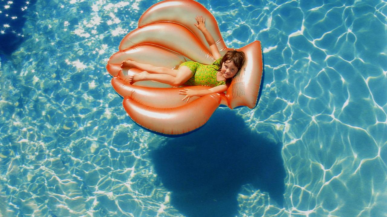 little girl on a pool toy in the water