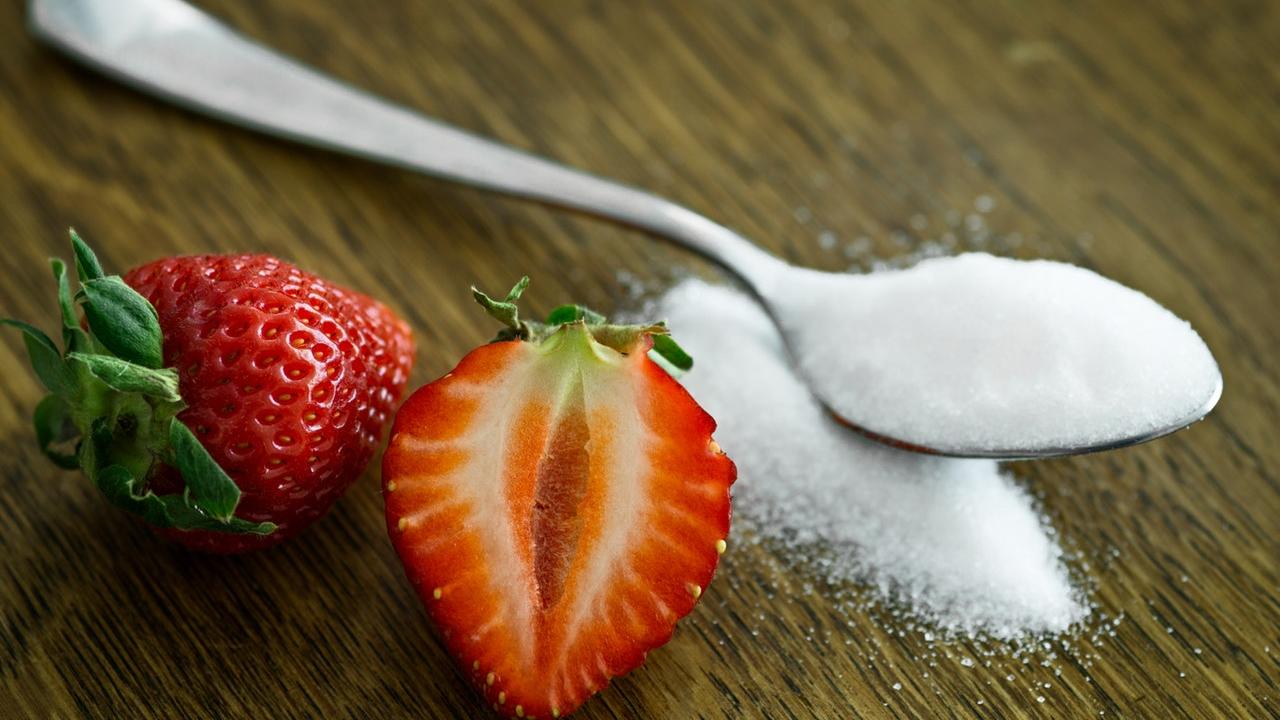 strawberry next to a tablespoon of sugar